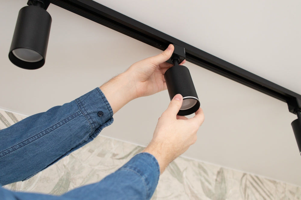 ผู้ชายกำลังติดตั้งโคมไฟแทรคไลท์ LED